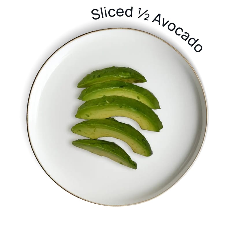 Sliced avocado on a white plate with a gold rim, against a white background.